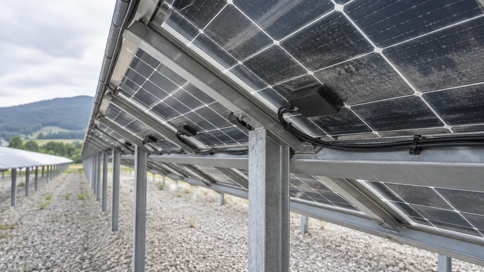 Rückansicht aufgeständerter bifazialer PV-Module mit sichtbarem Zellraster und leicht staubiger Glasfläche über Kies